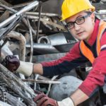 Worker in hard hat in front of pile of scrap metal.