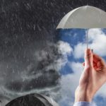 Concept image of a hand holding up an umbrella in a rain storm.