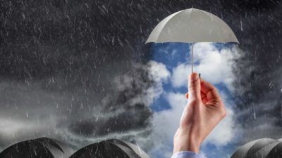 concept image of a hand holding up an umbrella in a rain storm.