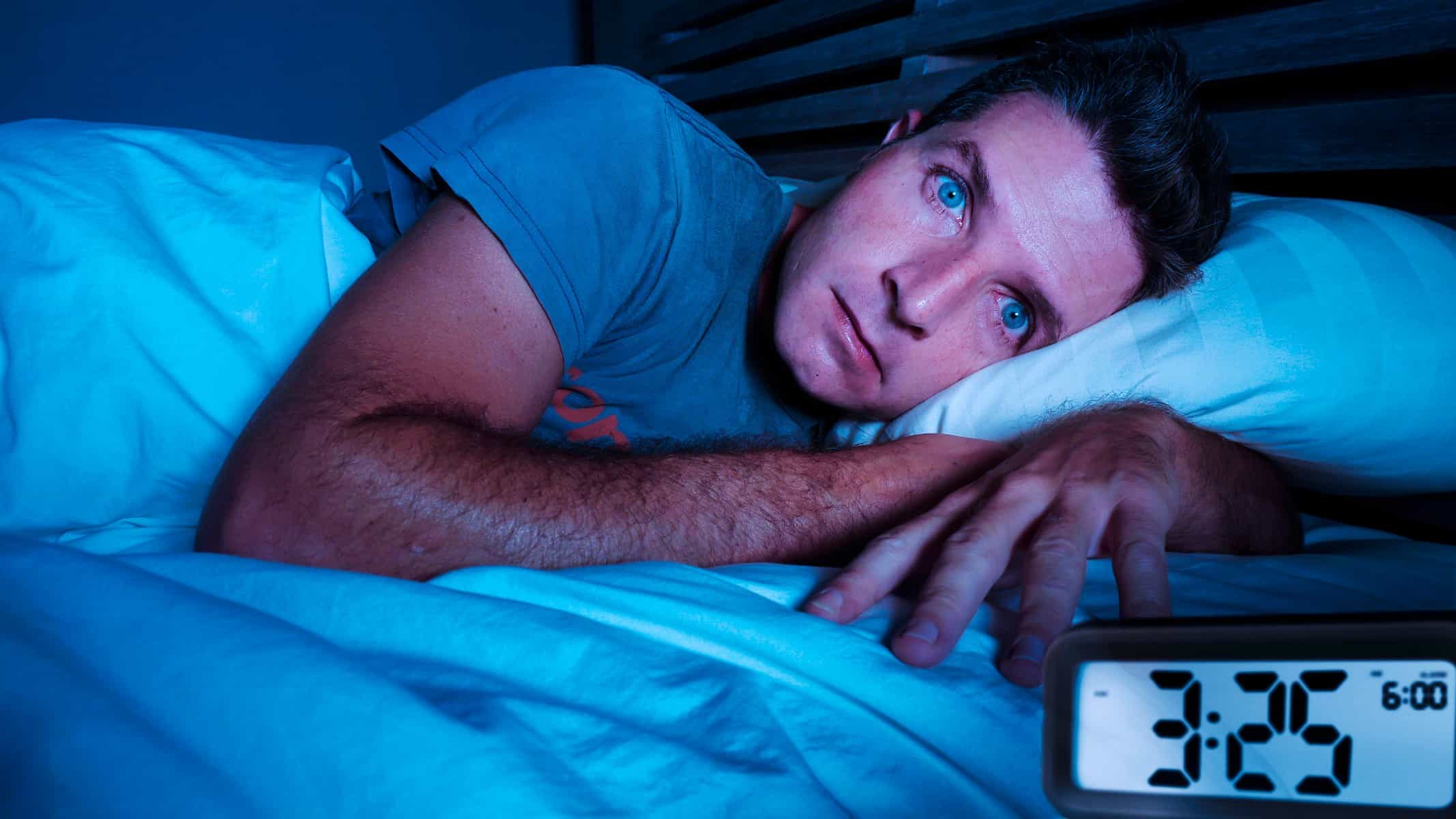 A man lies in bed wide awake in the middle of the night.