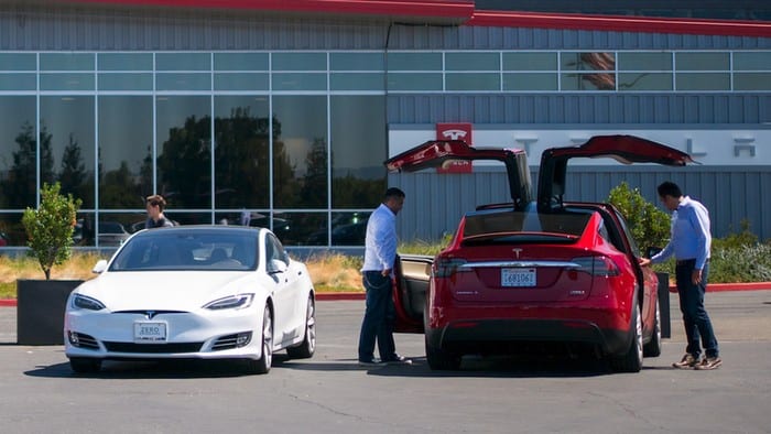 2 men checking a Tesla vehicle out.