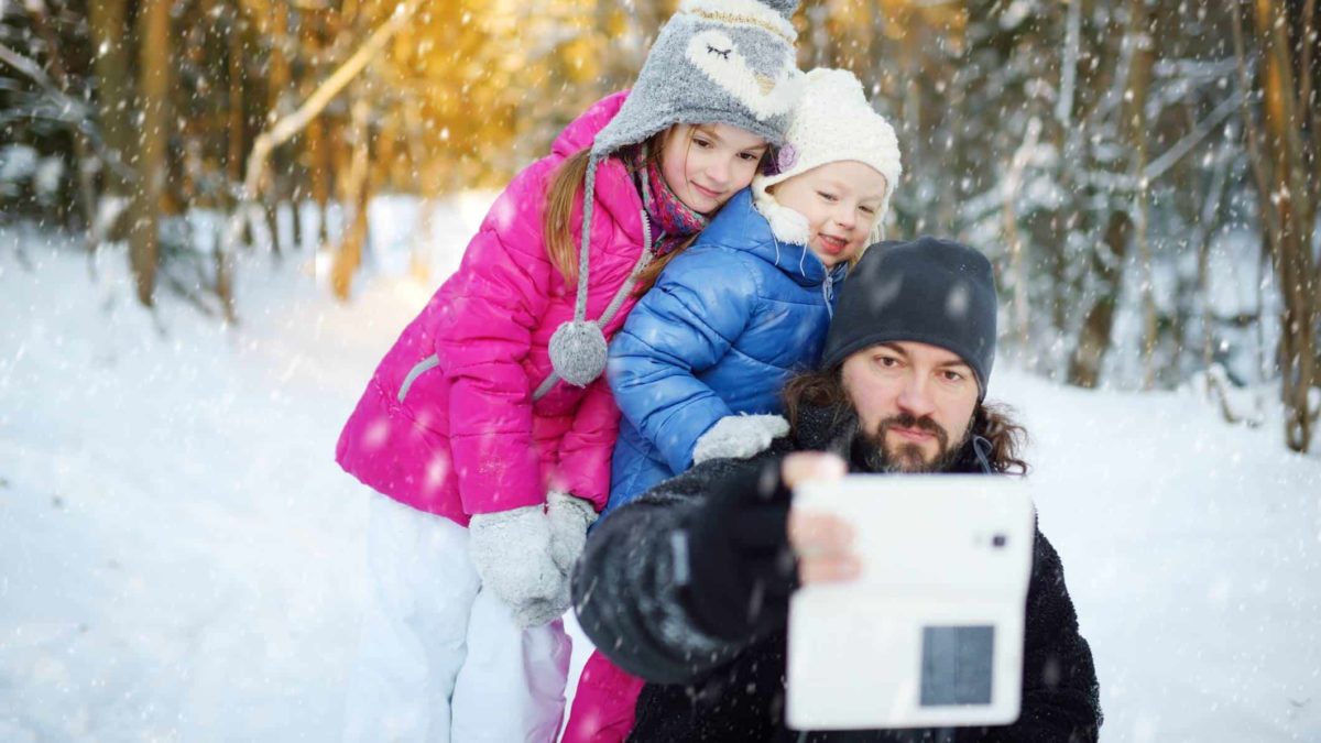 A father and his two daughters pose for a photo in the snow