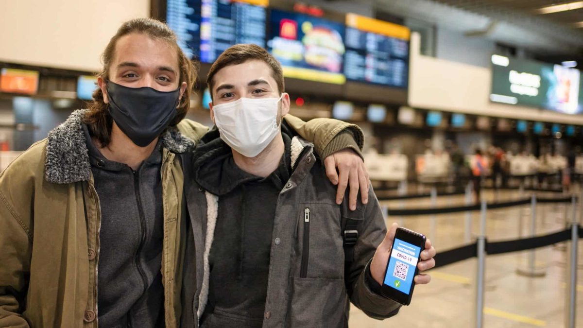 Two travellers show their vaccinati0on status at the airport as international travel opens up