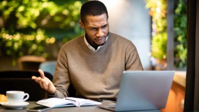 Man looks confused as he works at his laptop. watching the Magnis share price movements