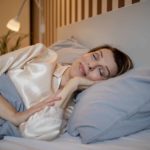 a mature woman sleeps peacefully in bed with a smile on her face as though she is very satisfied about something.