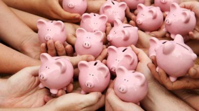 Many hands hold little piggy banks.