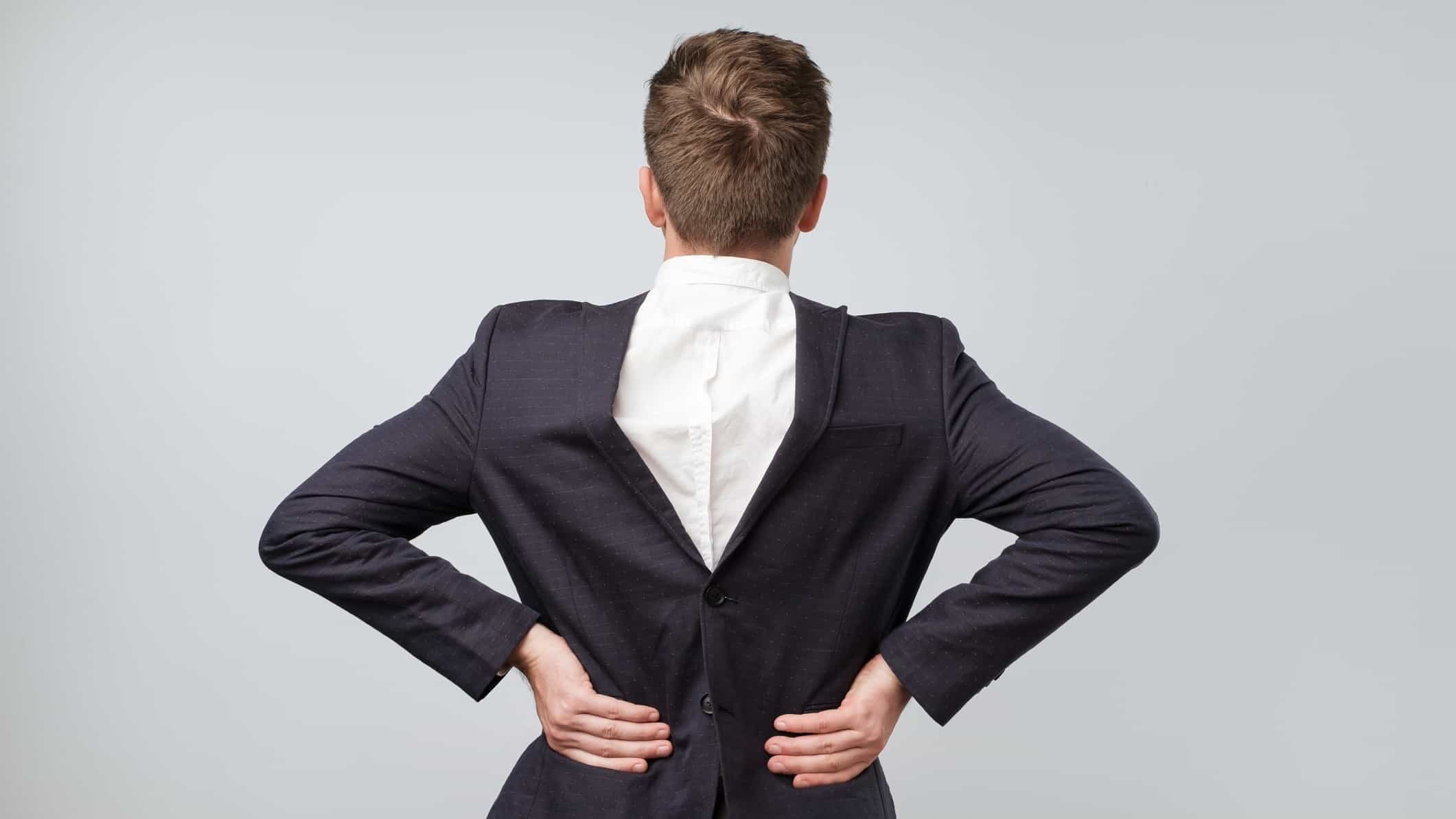 A man wears a suit in reverse, so the shirt and jacket are on backwards.