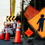 A street is filled with roadwork signs, flashing arrows and orange cones, causing traffic to slow.