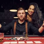 Man and woman sitting at casino table playing poker