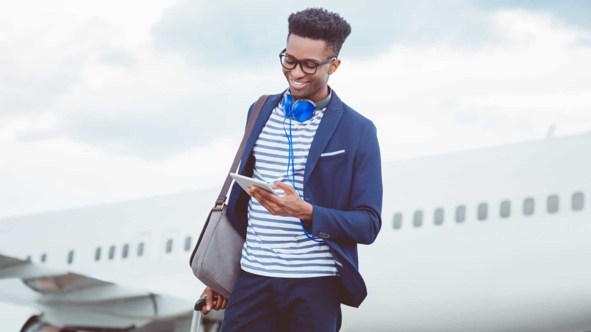 Young man smiles while on phone in front of plane.