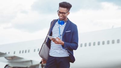Young man smiles while on phone in front of plane.