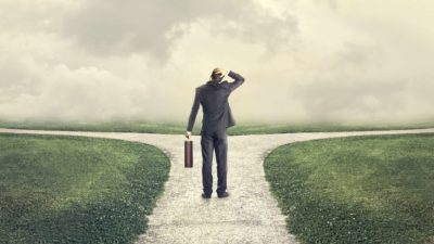 The back of a man standing in front of two roads going in different directions.