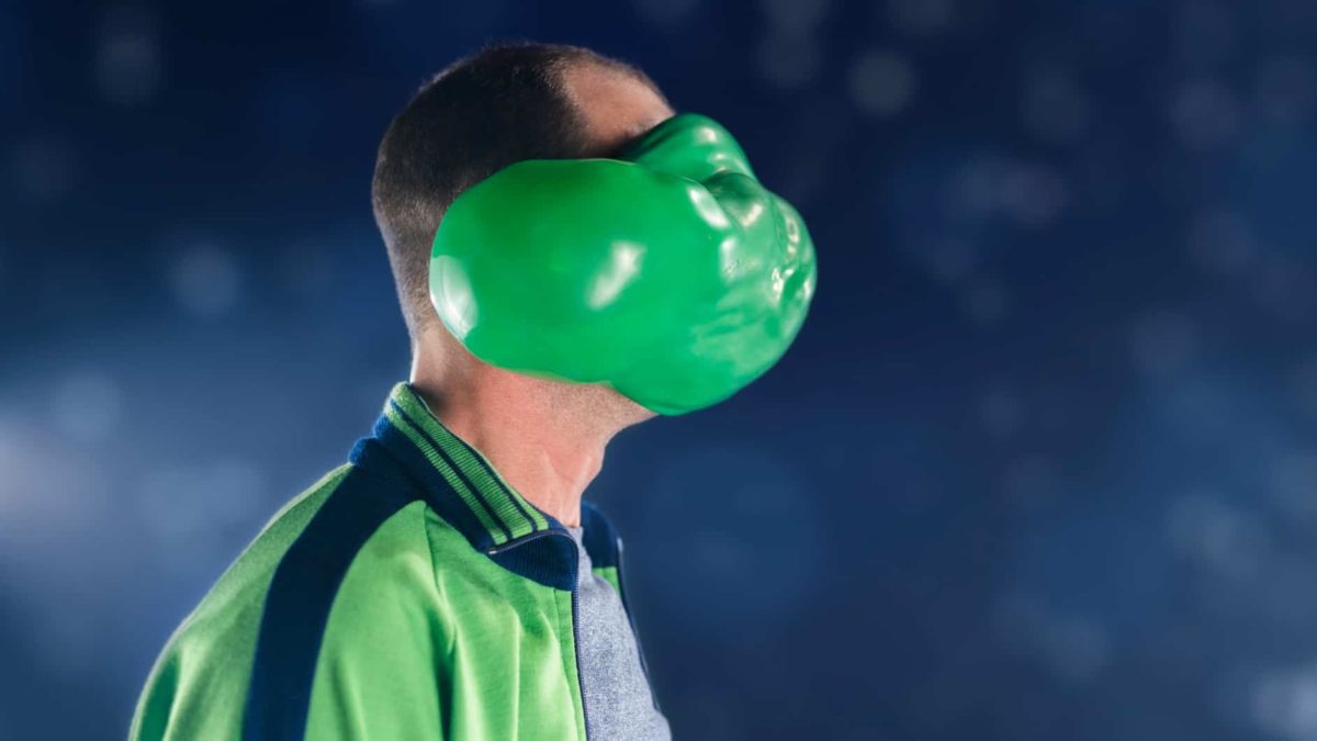 A green bubble or balloon bursts on a man's face.