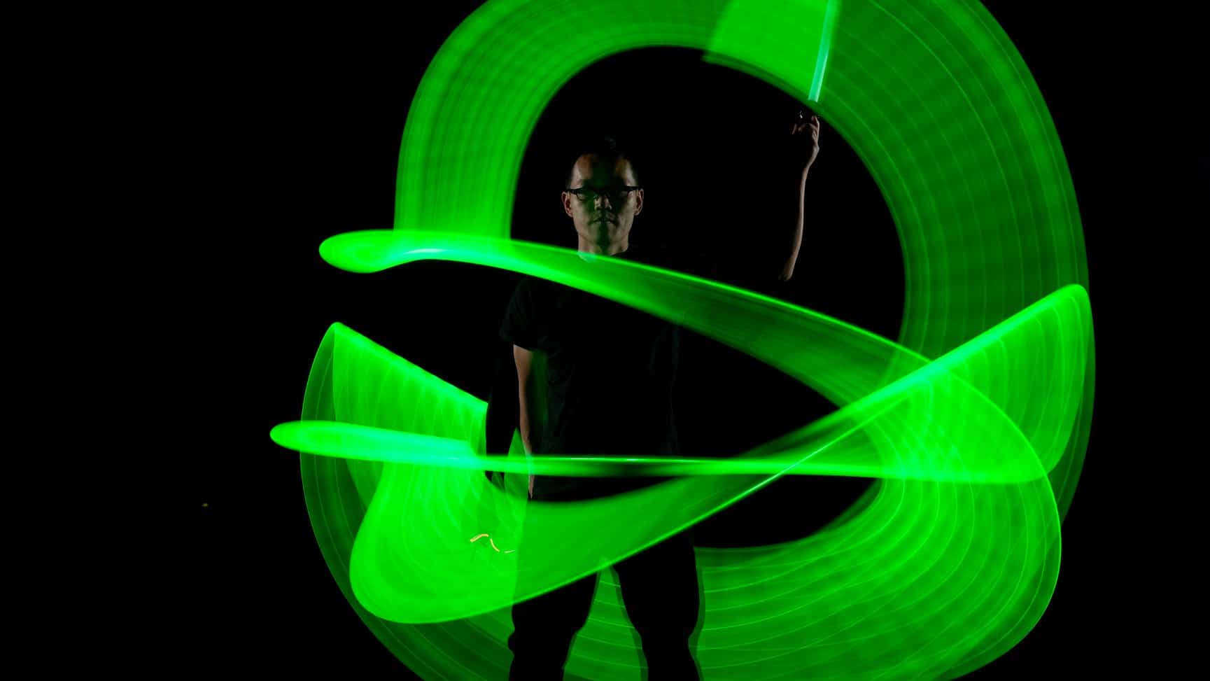 A man brandishes a green light against a dark backdrop