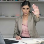 woman putting her hand up to stop sitting in white office