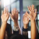 A group of hands up in the air as if signifying a hearty vote in favour of a motion.
