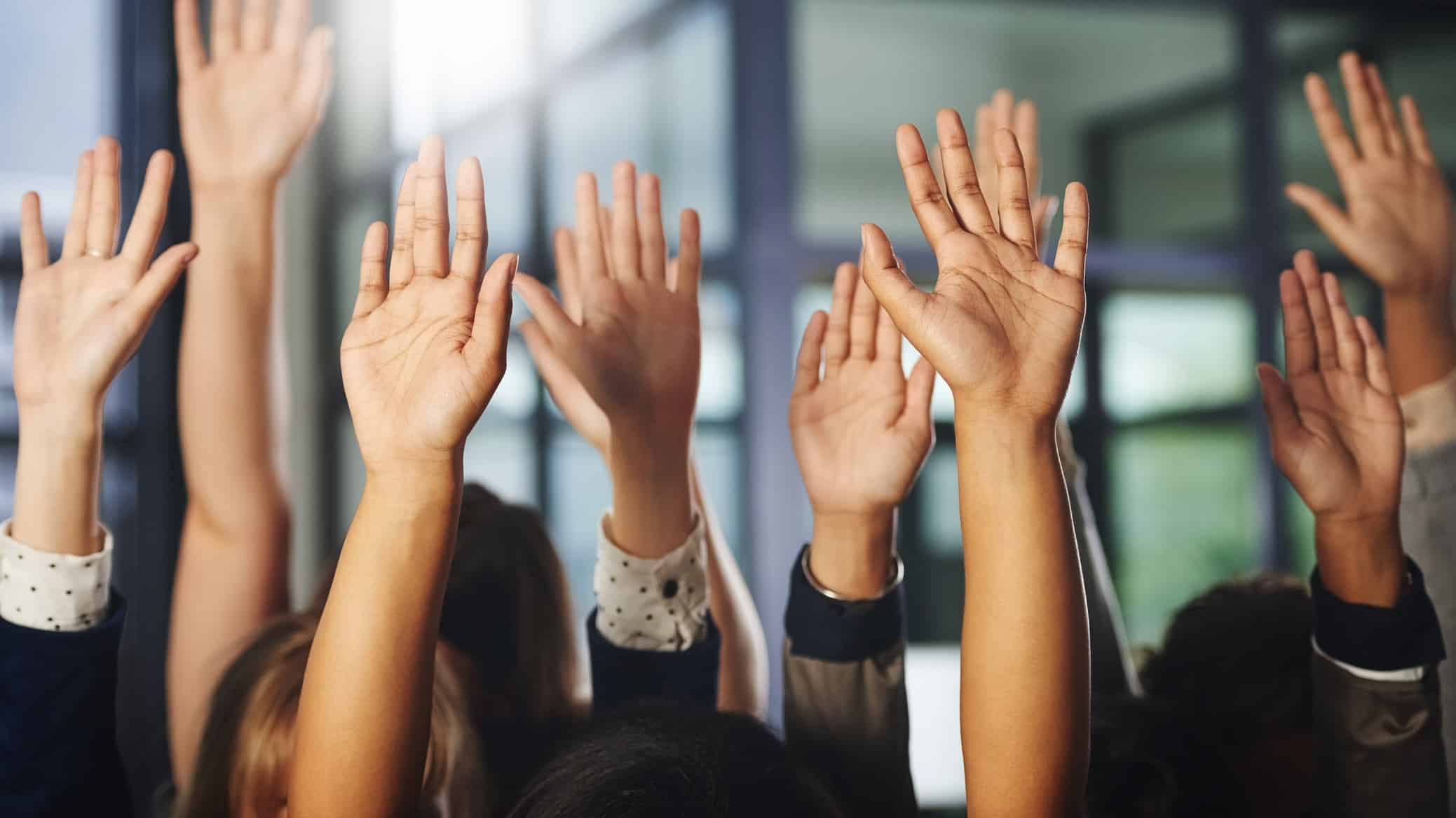 A group of hands up in the air as if signifying a hearty vote in favour of a motion or buying, buying, buying.