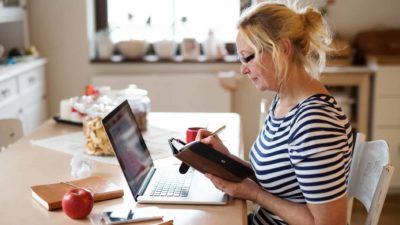 A female investor sits at her messy desk and marks dates in her diary for Zip announcements in 2022