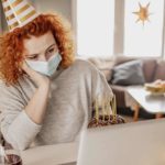 An investor sits at a table in front of her laptop with a party hat on her head and a cake next to her symbolising new year's eve but the 4DS Memory share price is plunging so she looks very disappointed and depressed