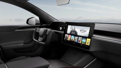 the interior of a Tesla car with its distinct computer screen style display with a grey sky outside the car windows