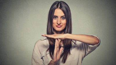 an attractive woman gives a time out signal with her hands, holding them in a T shape, indicating a trading halt.