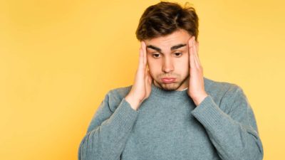 A worried man holds his head in his hands