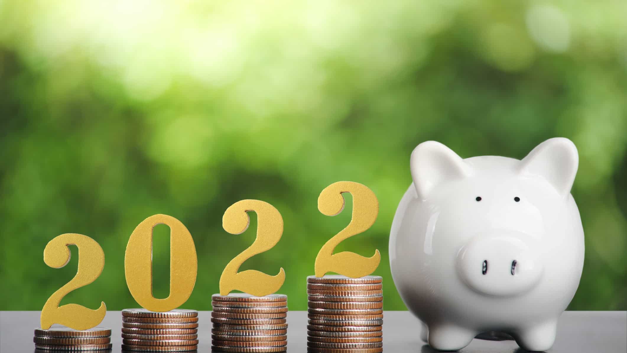 2022 written on a rising stack of coins with piggy bank on the side.