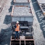 A worker in a hard hat reports an issue with the freight train on his walkie talkie.