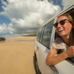 A woman has a big smile on her face as she drives her 4WD along the beach.