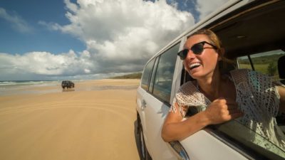 A woman has a big smile on her face as she drives her 4WD along the beach.