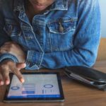A young woman checks her investments on her tablet.