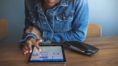 A young woman checks her investments on her tablet.
