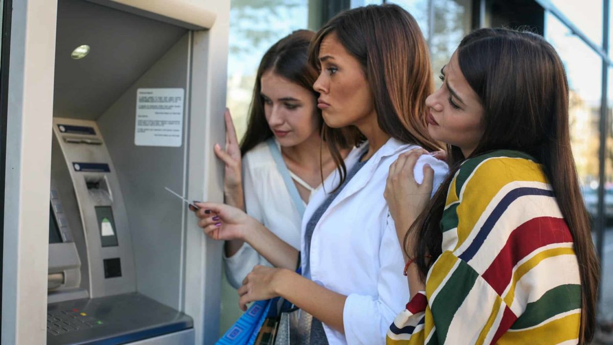Friends at an ATM looking sad.
