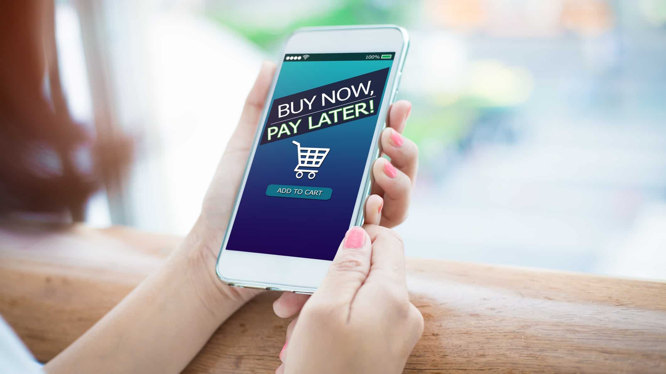 Buy now, pay later written on a smartphone with a shopping cart symbol at the bottom.