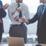 a group of 3 faceless business men stand together with one extending his hands dramatically as if protesting his treatment or stating his case passionately.