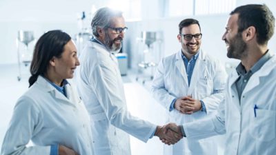 Health workers shake hands and congratulate each other on good news.