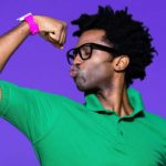 Man wearing green shirt and pink watch flexes his muscle. representing the strength in ASX shares at the moment