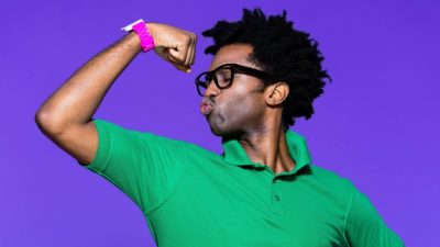 Man wearing green shirt and pink watch flexes his muscle. representing the strength in ASX shares at the moment