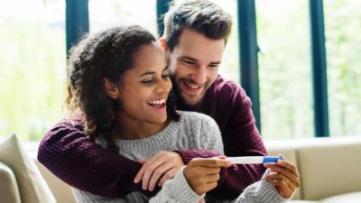 A couple smile as they look at a pregnancy test.