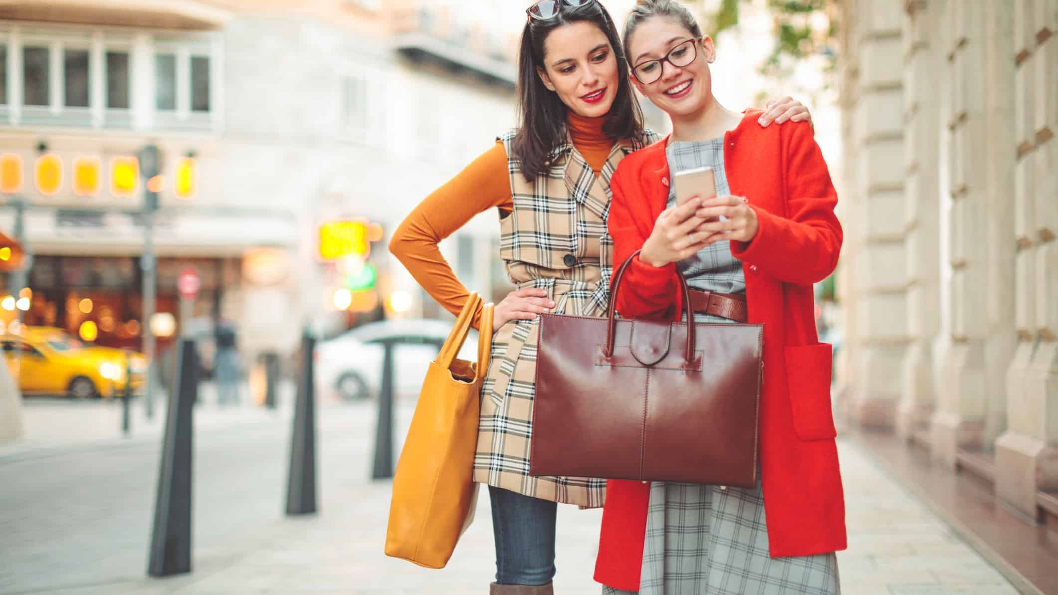 Two happy shoppers looking at a smartphone together.