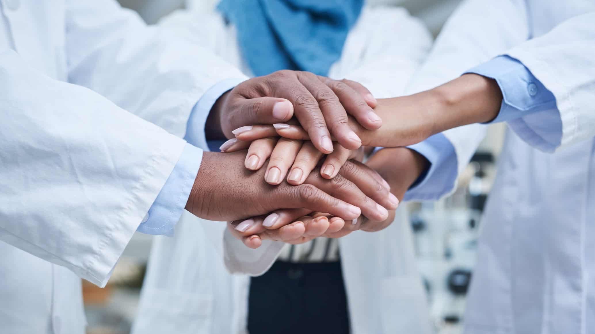 Medical or healthcare workers grasp hands in the universal expression of teamwork