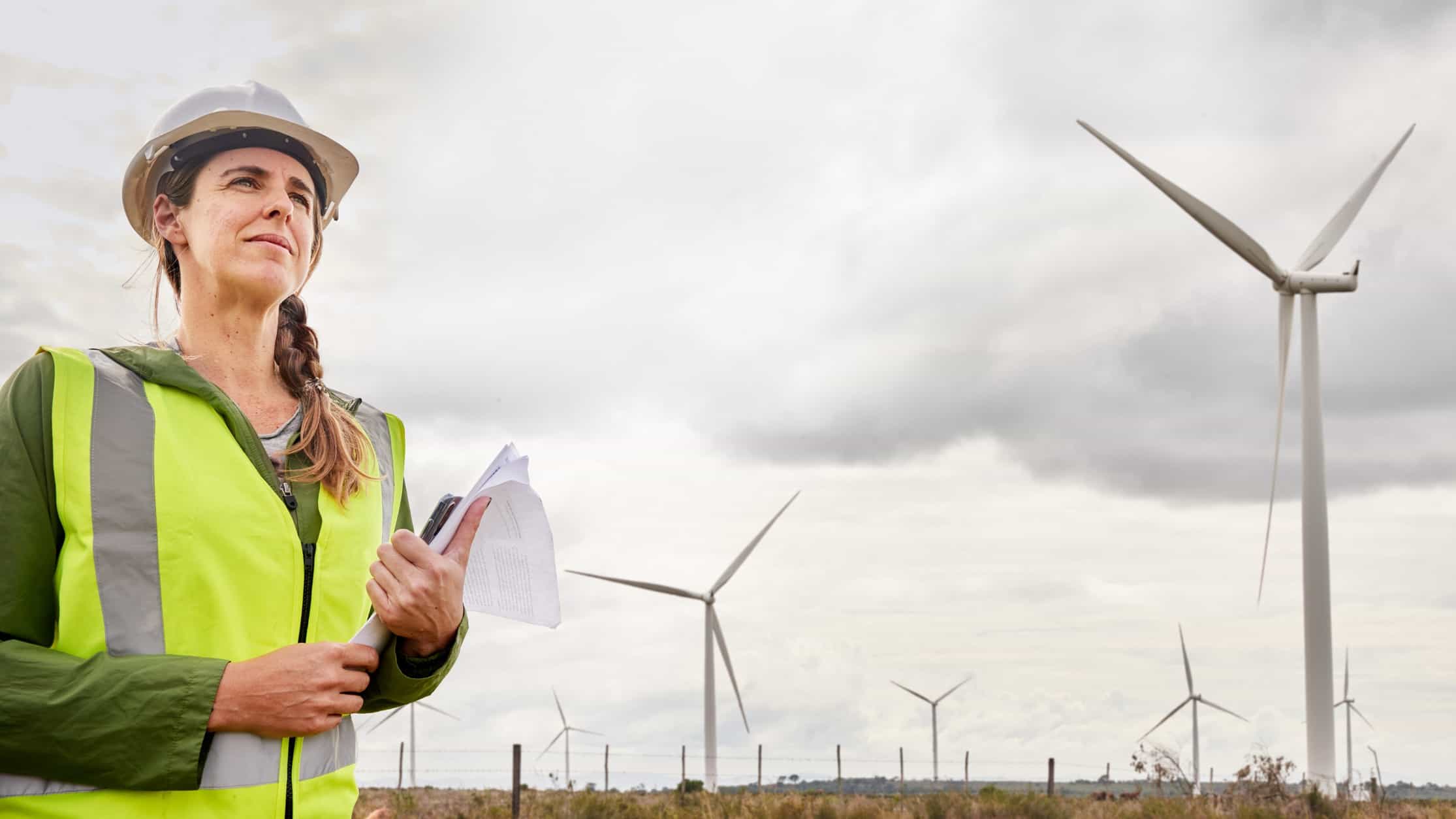 Woman standing in front of a wind farm.