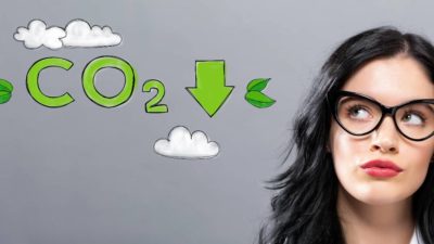 A woman looks sideways at a graphic near her head reading CO2 with a downward arrow.