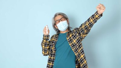 A man wearing a mask punches the air with joy after getting a negative COVID result on a rapid antigen test.