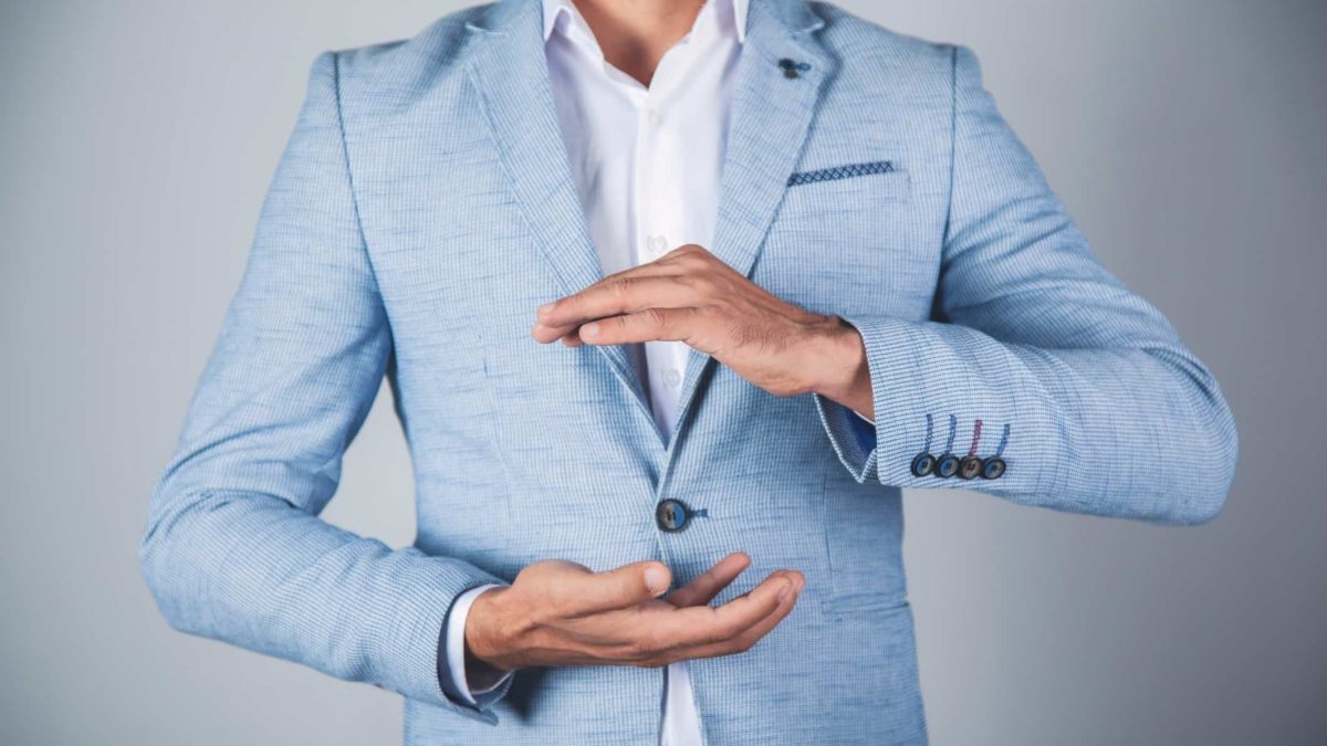 A businessman holds a neutral position, holding his hands with palms facing each other.