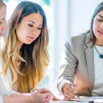 Three businesswomen collaborate around a table.