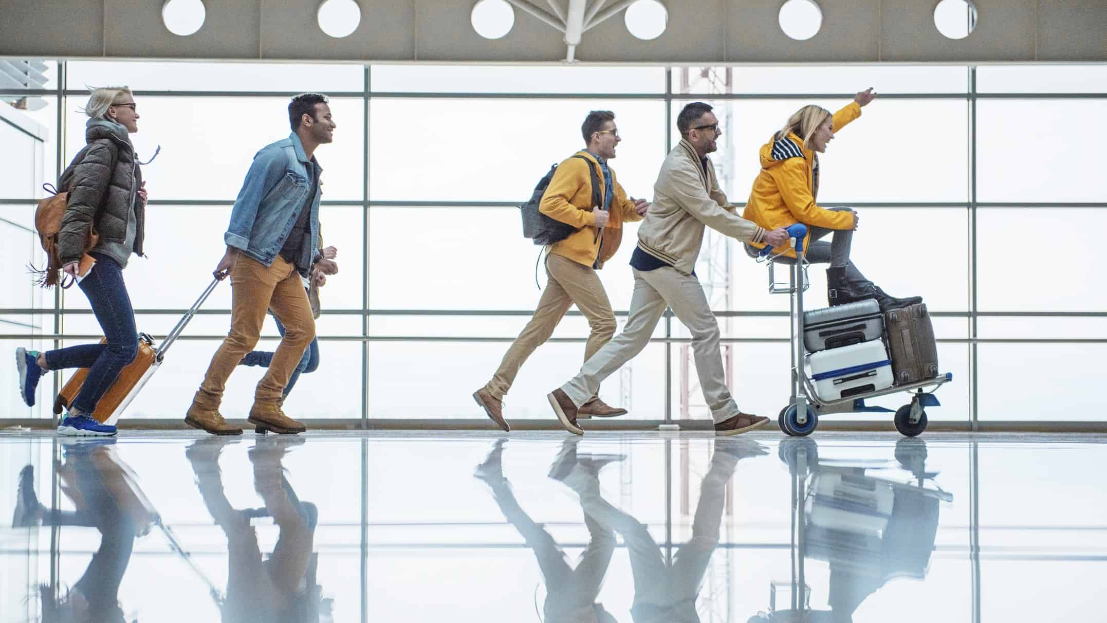A group of travellers run excitedly to the airport gate.