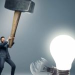 A man smashes light bulbs with a huge hammer.
