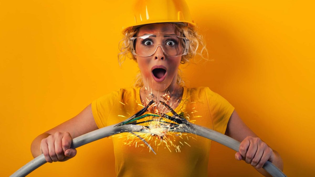 A woman wearing a hard hat holds two sparking wires together as energy surges between them. representing the rising Li-S Energy share price today