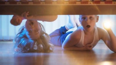 Two kids stare open-mouthed at what's under their bed.